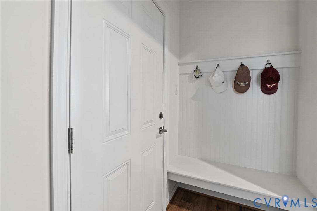 9337 Citrine Run, Henrico, VA 23238 Dedicated mudroom entry featuring white shaker-style cabinetry with recessed panel doors, white vertical shiplap wall paneling, wood-finish flooring, and a wall-mounted hook rail with four integrated hooks for organized storage and accessory display