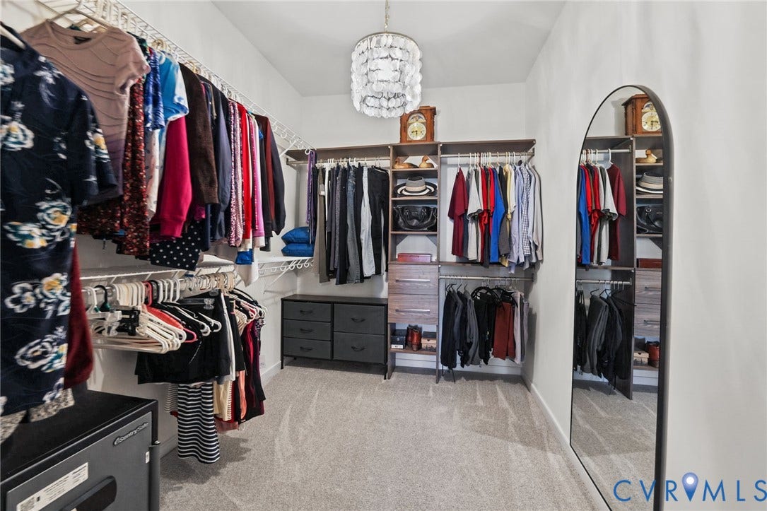 9337 Citrine Run, Henrico, VA 23238 Custom reach-in closet featuring multi-level hanging rods, built-in shelving, integrated storage drawers, and a tiered capiz shell pendant light fixture