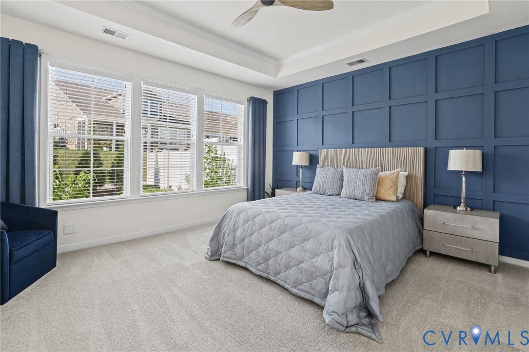 9337 Citrine Run, Henrico, VA 23238 Tray ceiling featuring a central wood-finish ceiling fan and a blue paneled accent wall with neutral wall-to-wall carpeting and large windows