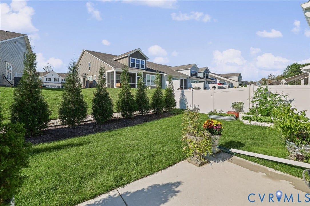 9337 Citrine Run, Henrico, VA 23238 Backyard featuring a concrete patio, perimeter vinyl fencing, lawn, and professional landscaping with evergreen trees