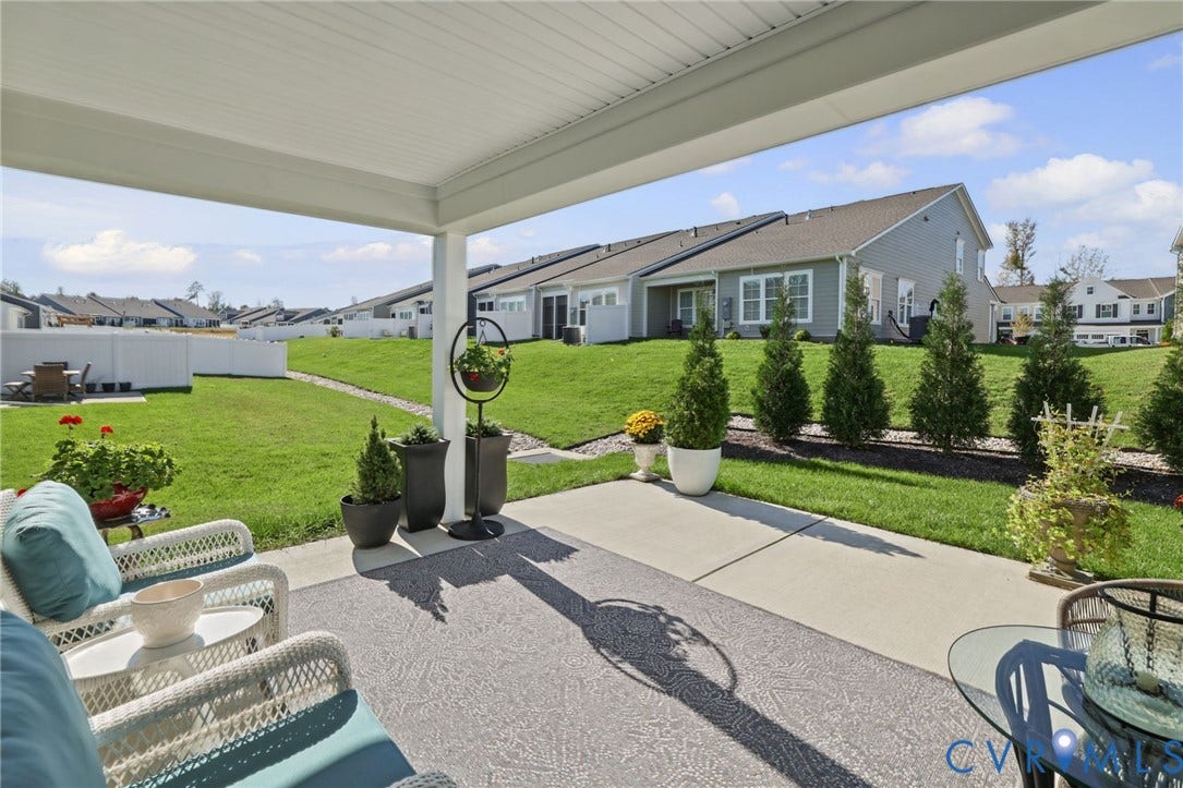 9337 Citrine Run, Henrico, VA 23238 Covered concrete patio featuring an overhead ceiling, expansive grass yard, vinyl privacy fencing, and landscaping with evergreen shrubs