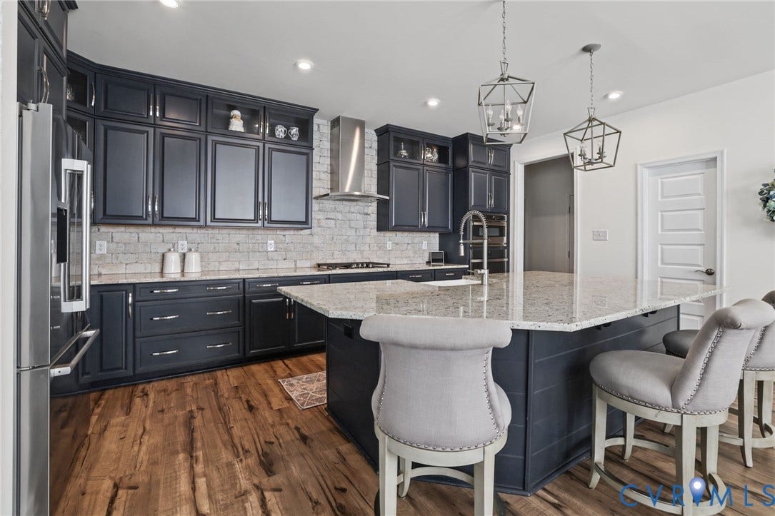 9337 Citrine Run, Henrico, VA 23238 Kitchen featuring navy cabinetry, stone-finish countertops, brick backsplash, wood-finish flooring, and pendant lighting