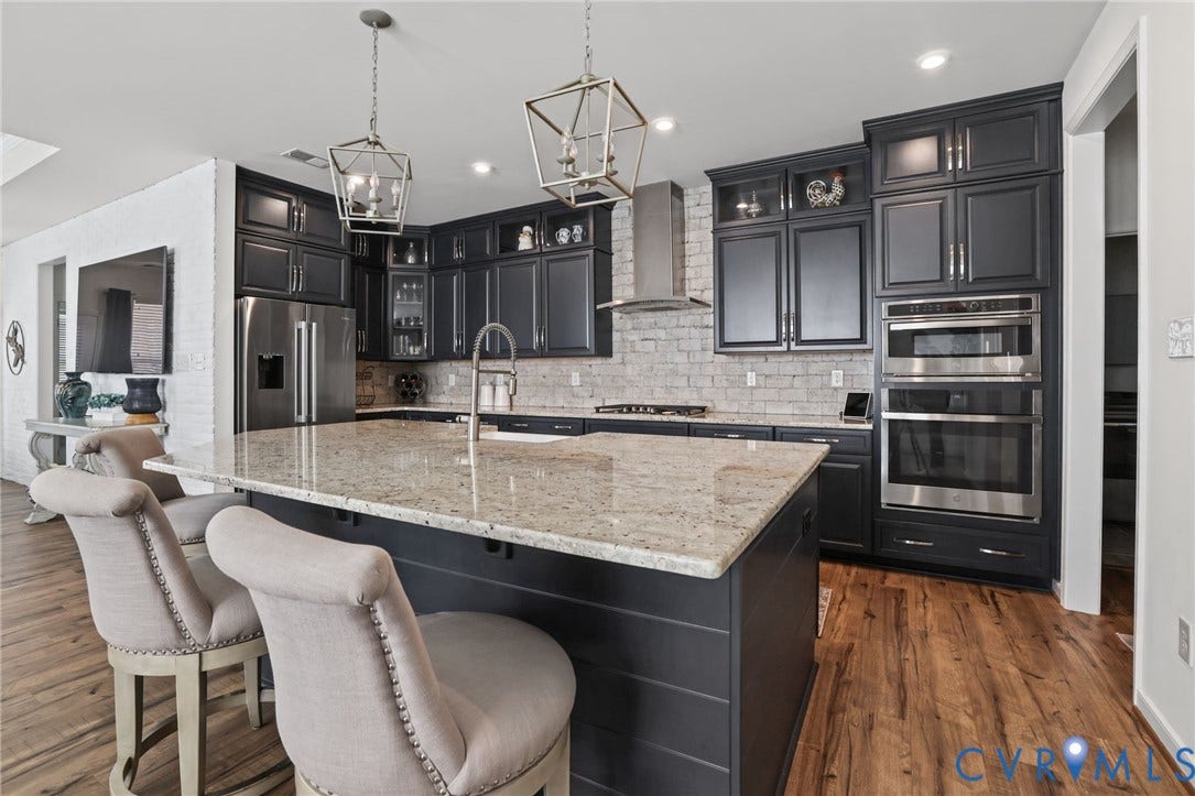 9337 Citrine Run, Henrico, VA 23238 Kitchen featuring dark cabinetry, stone countertops, a large center island, stainless steel double wall ovens, and a white brick backsplash