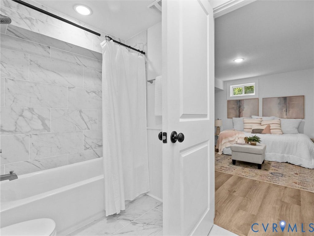 702 Westham Parkway, Westham, Henrico, VA 23229 White paneled door with matte black hardware, recessed ceiling lighting, light wood-finish flooring, and a white tub with tile surround
