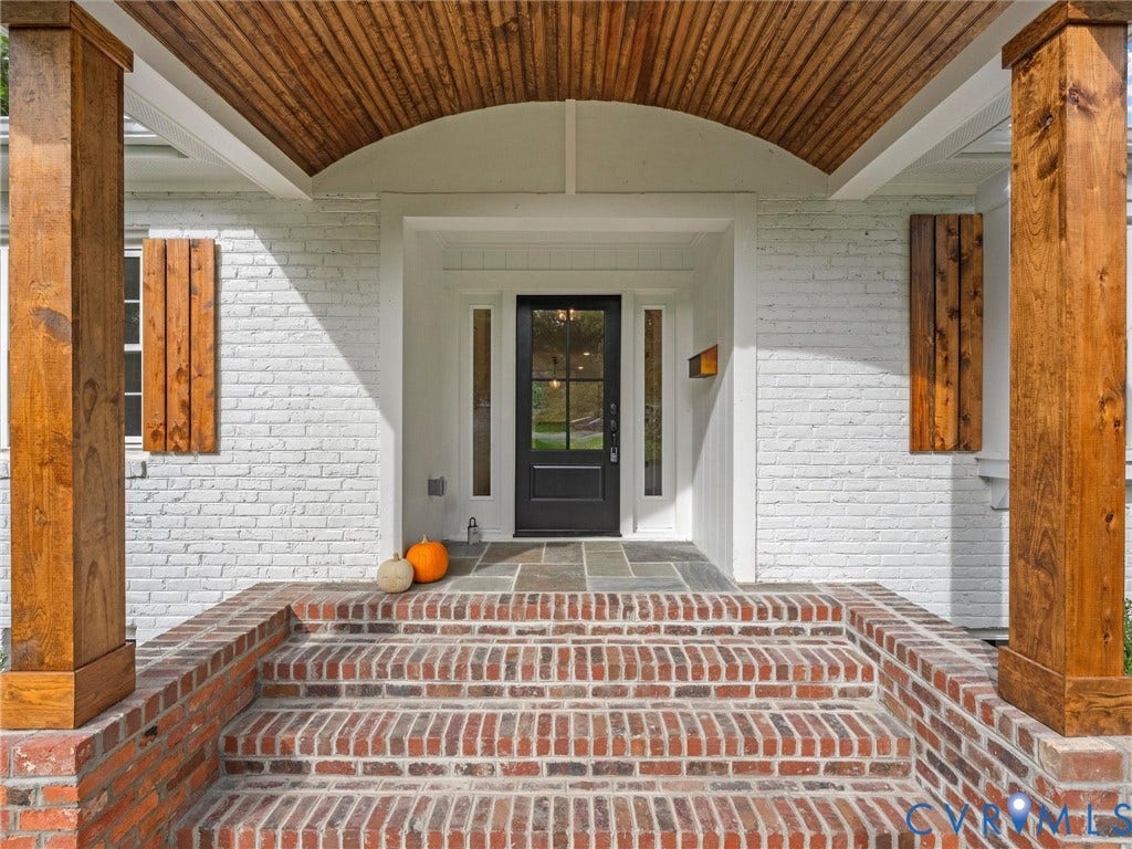 702 Westham Parkway, Westham, Henrico, VA 23229 Brick steps leading to a front porch with stone tile flooring, a dark entry door with glass panels, and wood-finished support columns