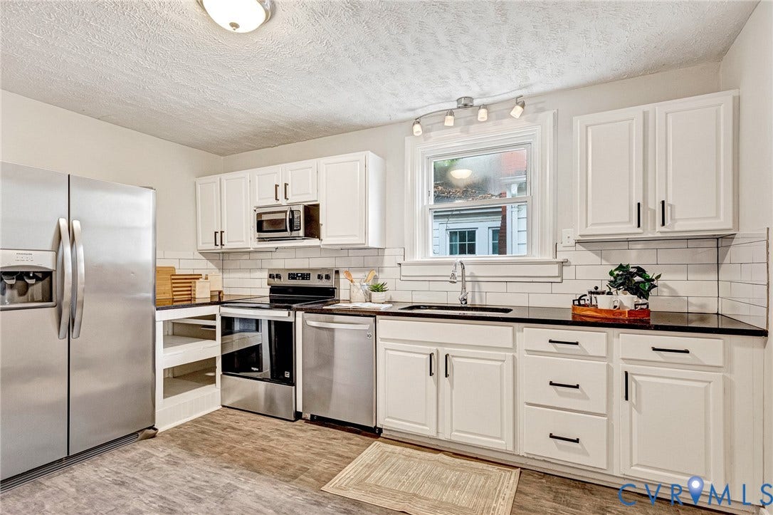 2817 Groveland Avenue, Green Park, Richmond, VA 23222 White cabinetry with black hardware, dark countertops, a subway tile backsplash, stainless steel appliances, and wood-finish flooring
