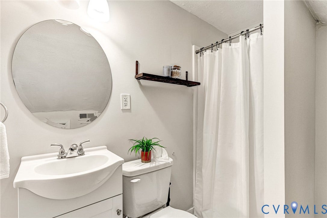 2817 Groveland Avenue, Green Park, Richmond, VA 23222 White vanity with integrated sink and chrome faucet, complemented by a round wall-mounted mirror