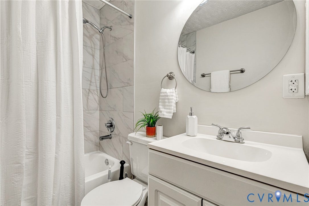 2817 Groveland Avenue, Green Park, Richmond, VA 23222 Bathroom featuring a white vanity with integrated sink, chrome faucet, oval mirror, and a tub with white subway tile surround