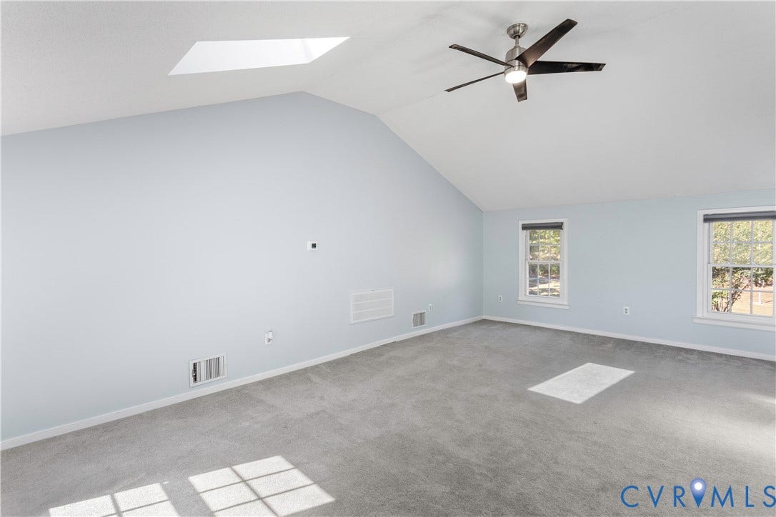 12380 Bienvenue Road, Bowles Acres, Rockville, VA 23146 Vaulted ceiling featuring a skylight, carpeted flooring, and a ceiling fan with integrated lighting, complemented by two double-hung windows