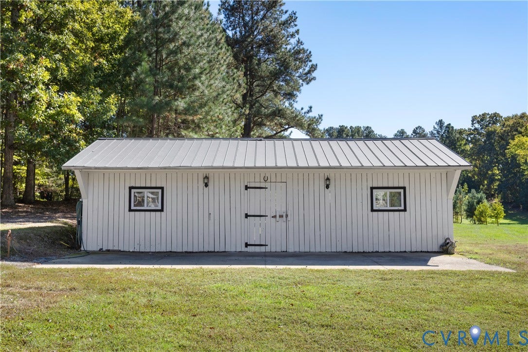 12380 Bienvenue Road, Bowles Acres, Rockville, VA 23146 Detached outbuilding featuring vertical board siding, a standing-seam metal roof, two exterior wall-mounted lanterns, and double-entry doors with heavy-duty strap hinges