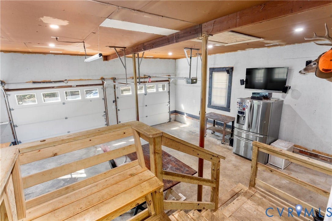 12380 Bienvenue Road, Bowles Acres, Rockville, VA 23146 Multi-bay garage featuring overhead doors with glass panel inserts, recessed lighting, exposed structural ceiling beams, and integrated wood staircase railings