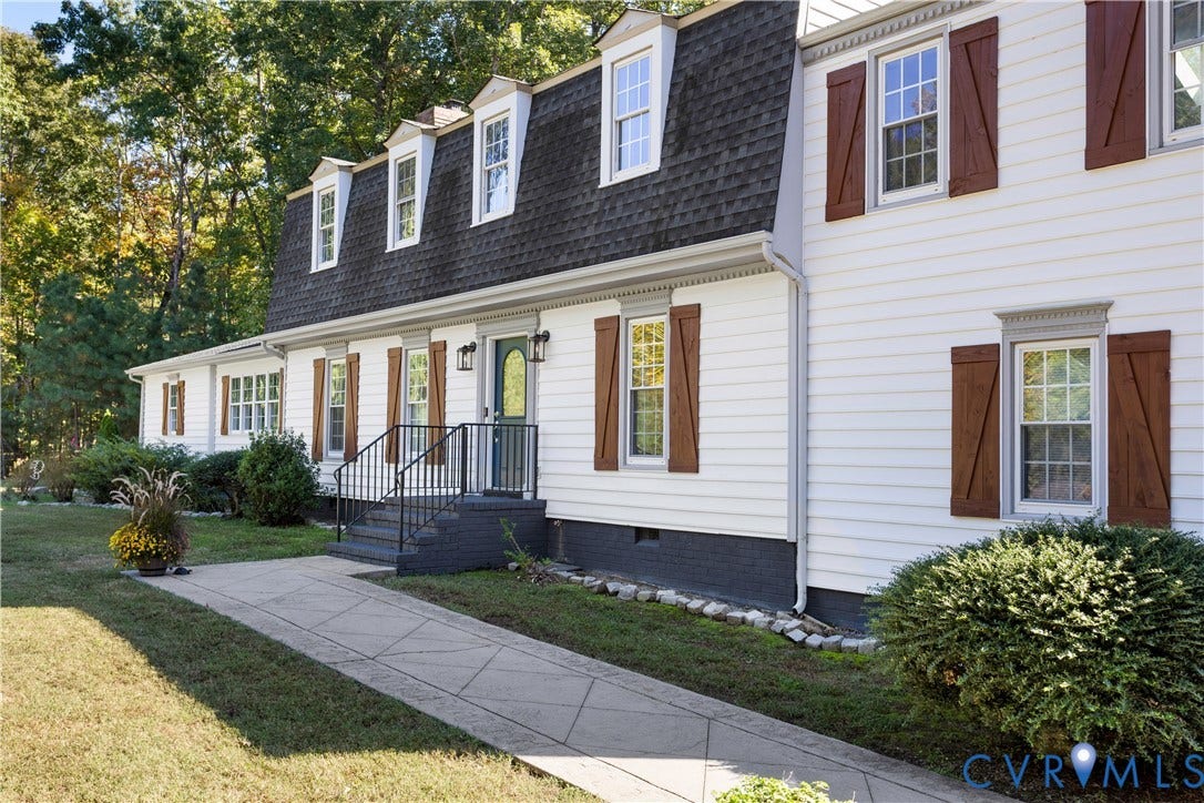 12380 Bienvenue Road, Bowles Acres, Rockville, VA 23146 Dutch Colonial exterior featuring white horizontal siding, dark-toned shutters, a gambrel roofline with dormer windows, and a paved walkway leading to metal exterior steps