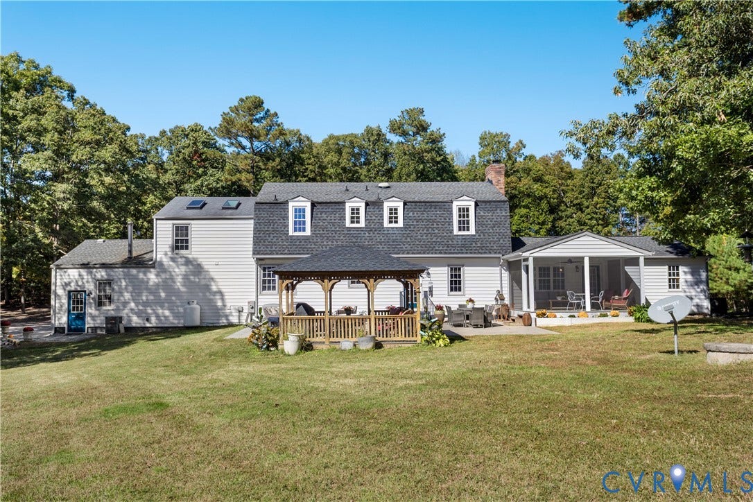12380 Bienvenue Road, Bowles Acres, Rockville, VA 23146 Exterior of the multi-level home featuring light-toned horizontal siding, a mansard roof, a wooden gazebo, a covered patio, and expansive grounds surrounded by mature trees