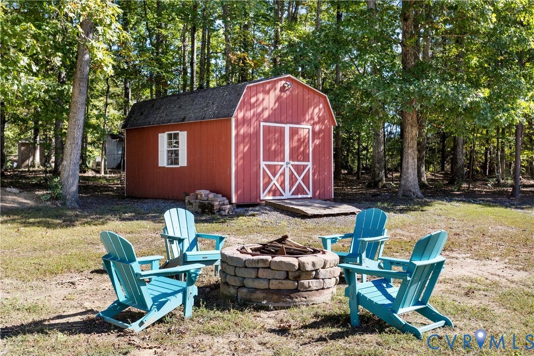 12380 Bienvenue Road, Bowles Acres, Rockville, VA 23146 Barn-style storage structure featuring double doors, white trim accents, and a ramp, complemented by a circular stone-block fire pit