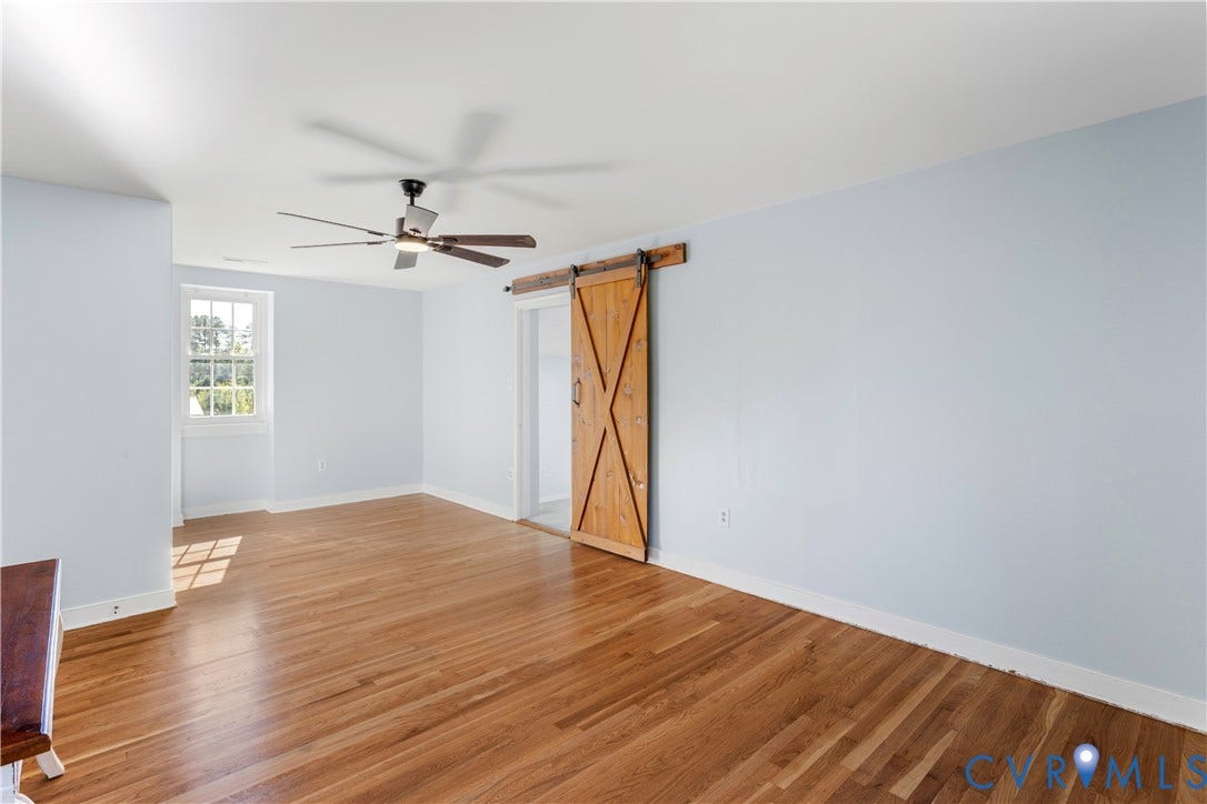 12380 Bienvenue Road, Bowles Acres, Rockville, VA 23146 2nd floor primary a sliding wood barn door, and a ceiling-mounted fan with integrated lighting. New refinished hardwood flooring! attached full bath. Adjoining multipurpose carpeted room HUGE!