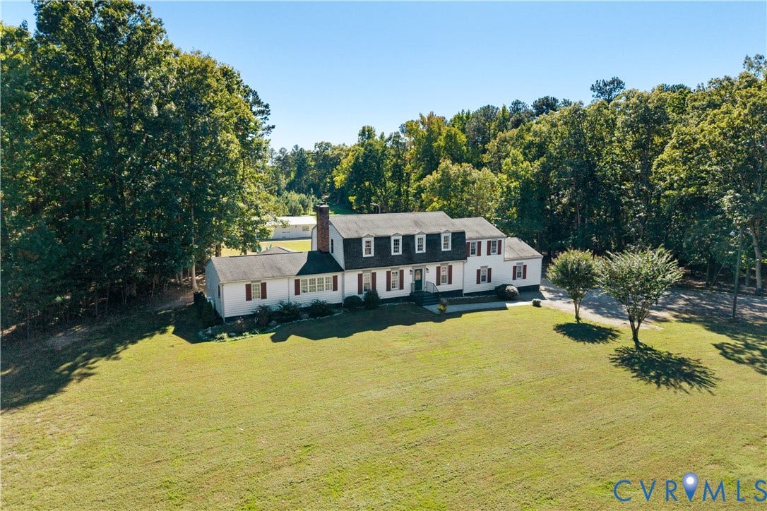 12380 Bienvenue Road, Bowles Acres, Rockville, VA 23146 Two-story colonial exterior featuring a brick chimney, gabled dormers, decorative window shutters, and a sprawling lawn surrounded by mature trees