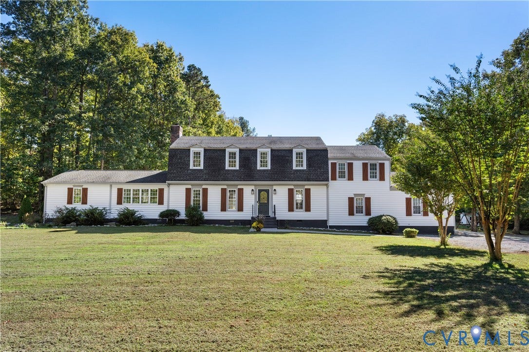 12380 Bienvenue Road, Bowles Acres, Rockville, VA 23146 Colonial-style exterior featuring vinyl siding, a dark-toned mansard roof, symmetrical window placement, decorative shutters, and an expansive front lawn