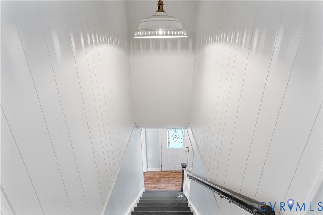 12380 Bienvenue Road, Bowles Acres, Rockville, VA 23146 Stairway featuring white vertical paneled walls, a metal dome pendant light, and a dark-toned handrail.