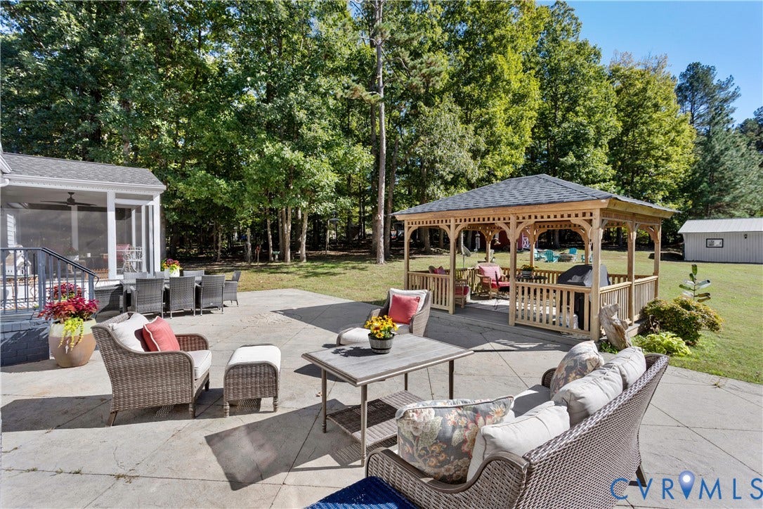 12380 Bienvenue Road, Bowles Acres, Rockville, VA 23146 Spacious concrete patio featuring a wooden gazebo with a shingled roof, a covered porch, and mature surrounding woodland