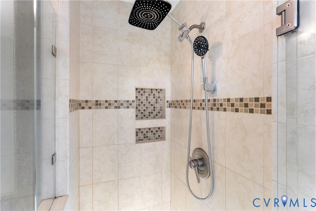12380 Bienvenue Road, Bowles Acres, Rockville, VA 23146 Walk-in shower featuring oversized square rainfall showerhead, adjustable handheld sprayer, neutral-toned wall tiling, decorative mosaic tile inlay, and dual built-in recessed wall niches