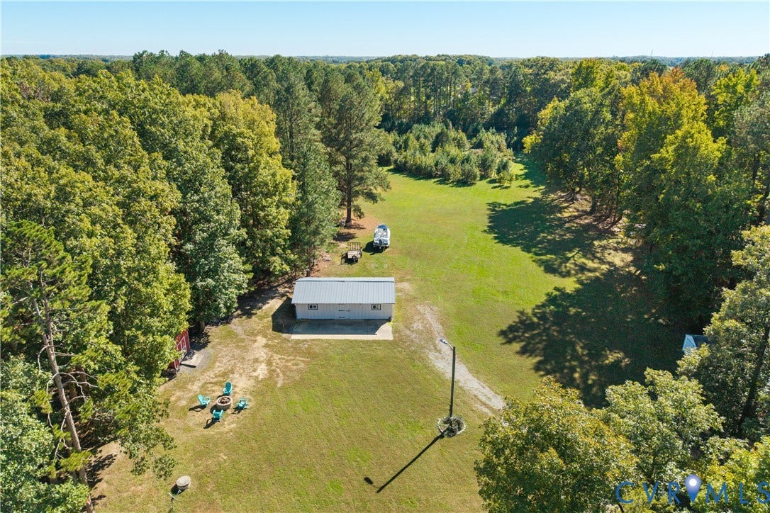 12380 Bienvenue Road, Bowles Acres, Rockville, VA 23146 Expansive acreage featuring mature perimeter trees, an open grass field, and a detached metal-roofed structure with a concrete pad