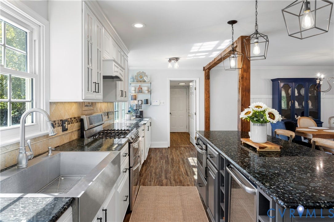 12380 Bienvenue Road, Bowles Acres, Rockville, VA 23146 Kitchen featuring a farmhouse-style sink, dark stone countertops, custom cabinetry, wood-finish flooring, and exposed wooden support beam with geometric pendant lighting