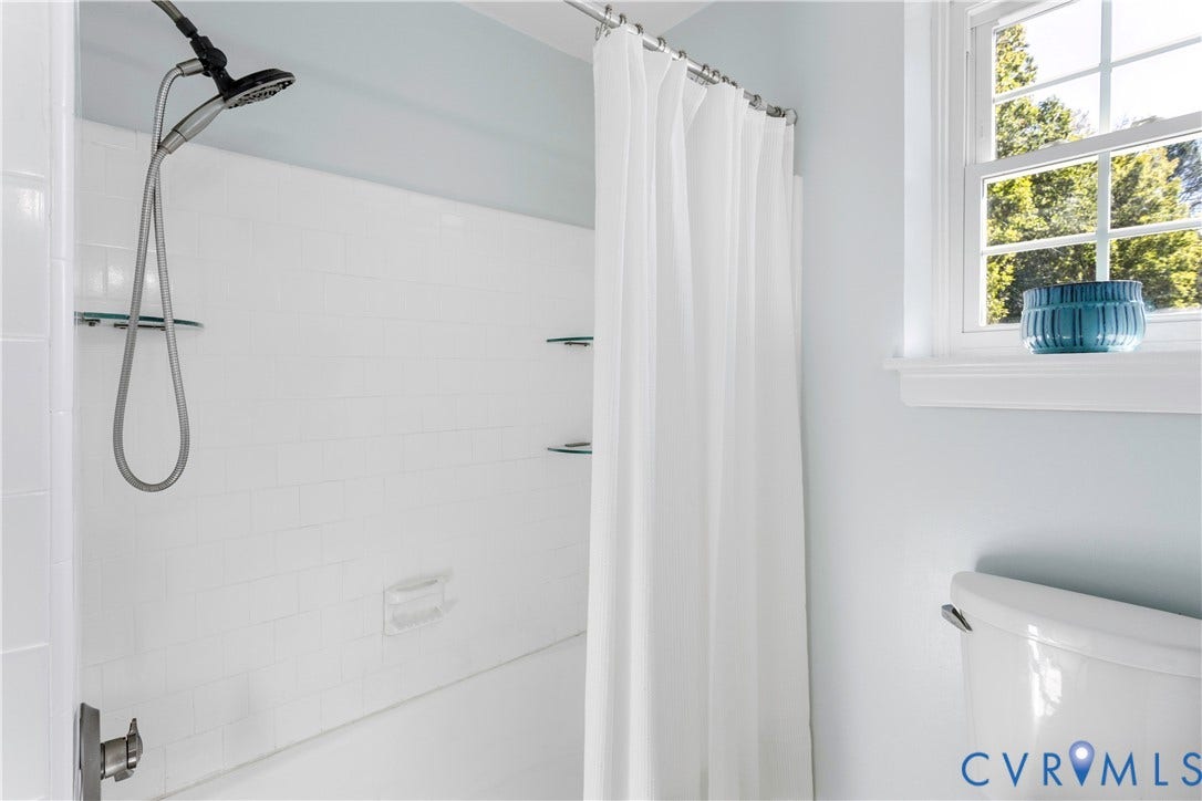 12380 Bienvenue Road, Bowles Acres, Rockville, VA 23146 Shower area featuring white subway tile surround, built-in glass shelving, multi-function shower head, and a double-hung window