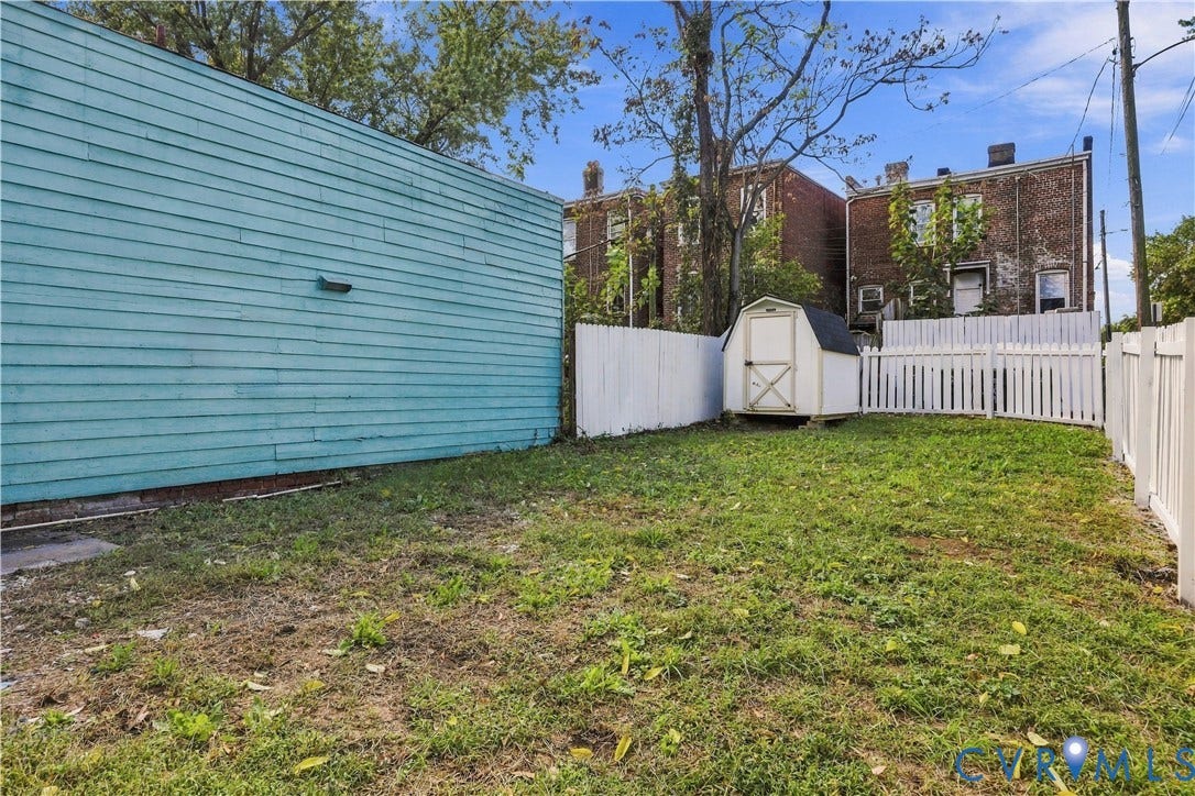 Private outdoor space featuring a fenced lawn area and a detached storage shed