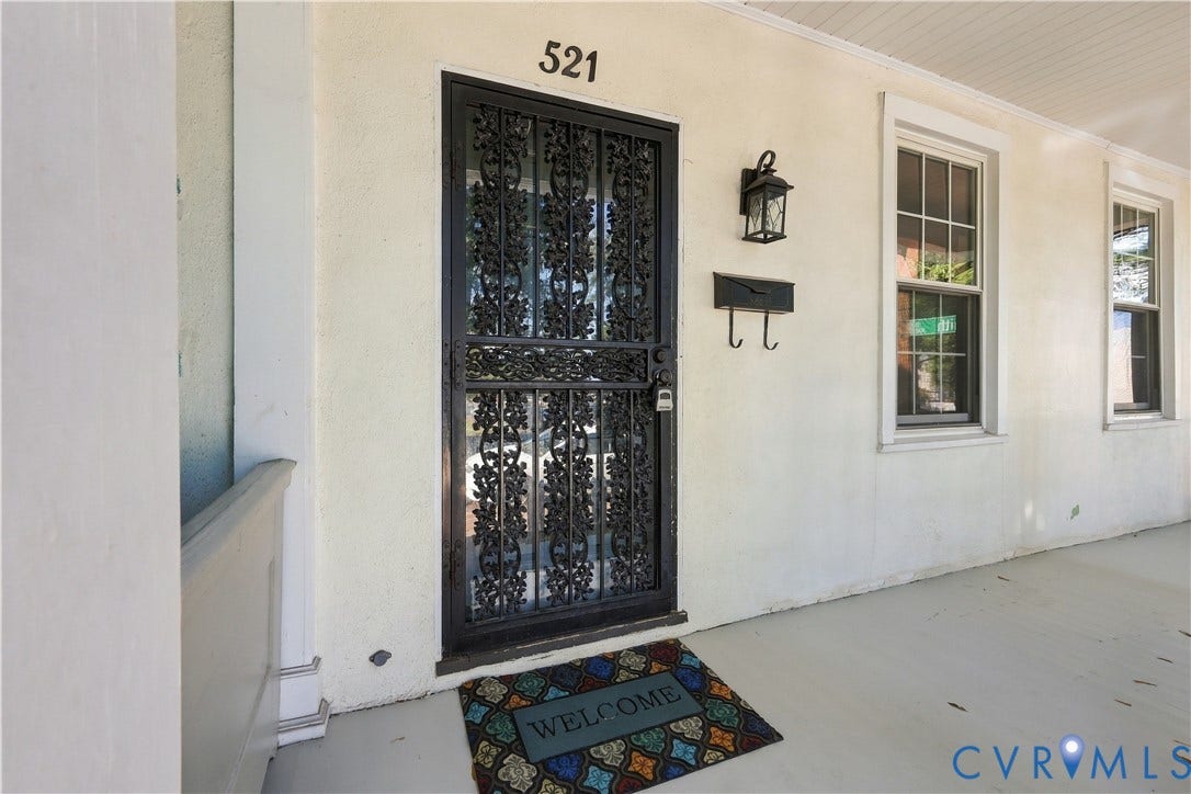 Covered porch featuring smooth-finish stucco exterior, decorative metal security door, dual-pane windows, and wall-mounted exterior lighting