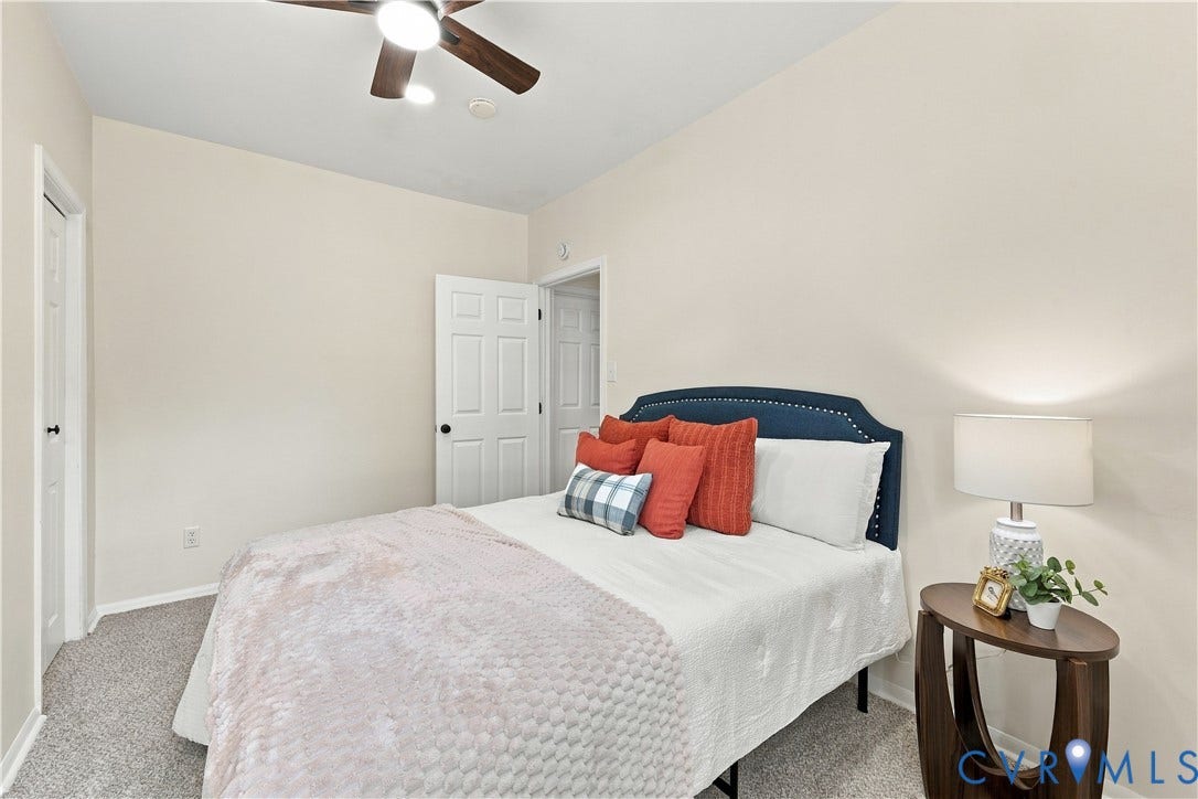 Neutral-toned interior featuring wall-to-wall carpeting, a ceiling-mounted light fixture with fan, and multi-panel interior doors