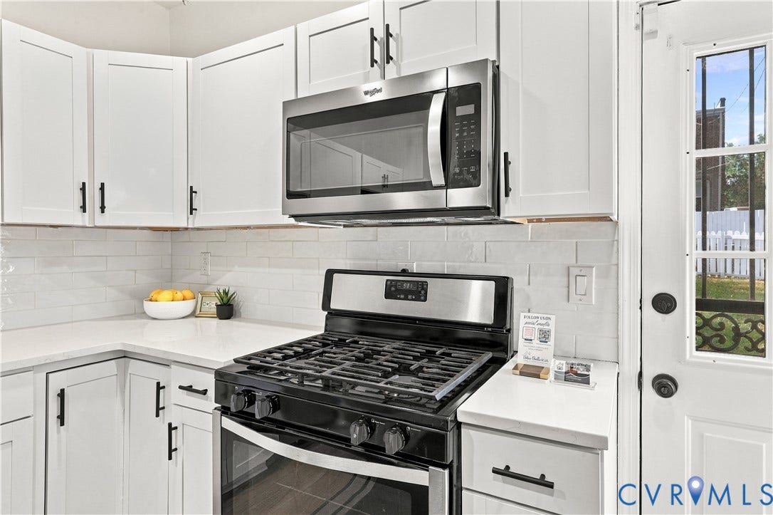 Kitchen featuring white cabinetry with matte black hardware, stainless steel gas range, built-in stainless steel microwave, light-toned countertops, and a white subway tile backsplash