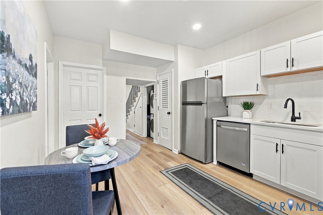 Kitchen featuring white shaker-style cabinetry, stainless steel appliances, subway tile backsplash, matte black faucet, and wood-finish flooring