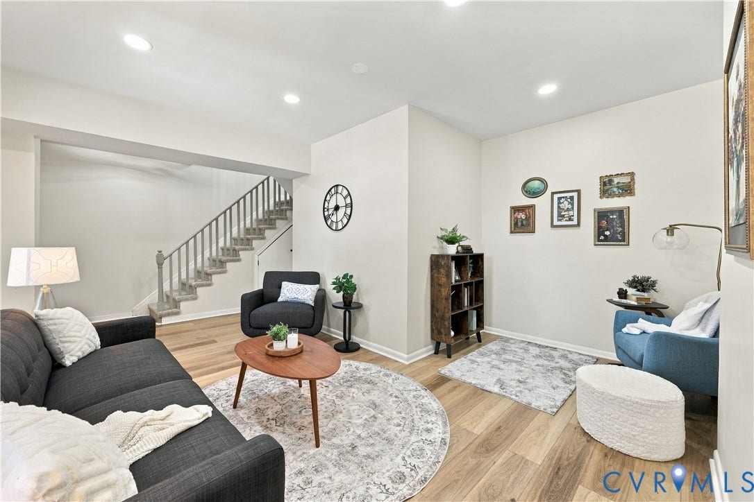 Living area featuring wood-finish flooring, recessed lighting, and a staircase with vertical balusters