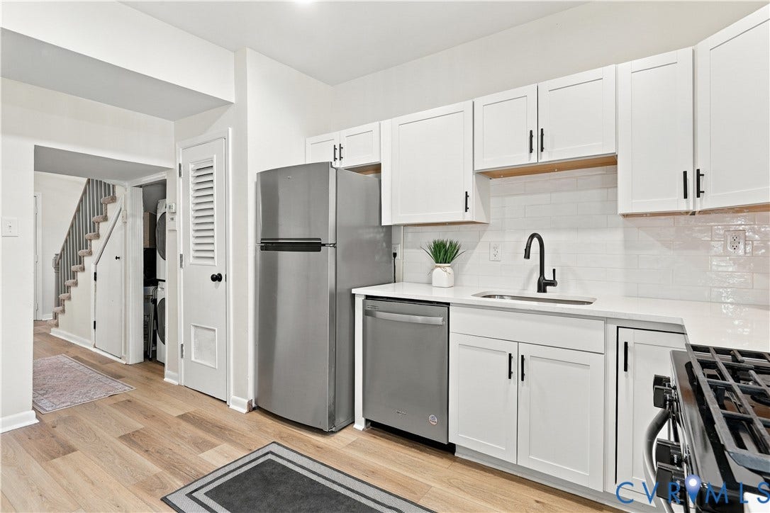 Kitchen featuring white shaker-style cabinetry, stainless steel appliances, white subway tile backsplash, light-toned wood-finish flooring, and a matte black gooseneck faucet