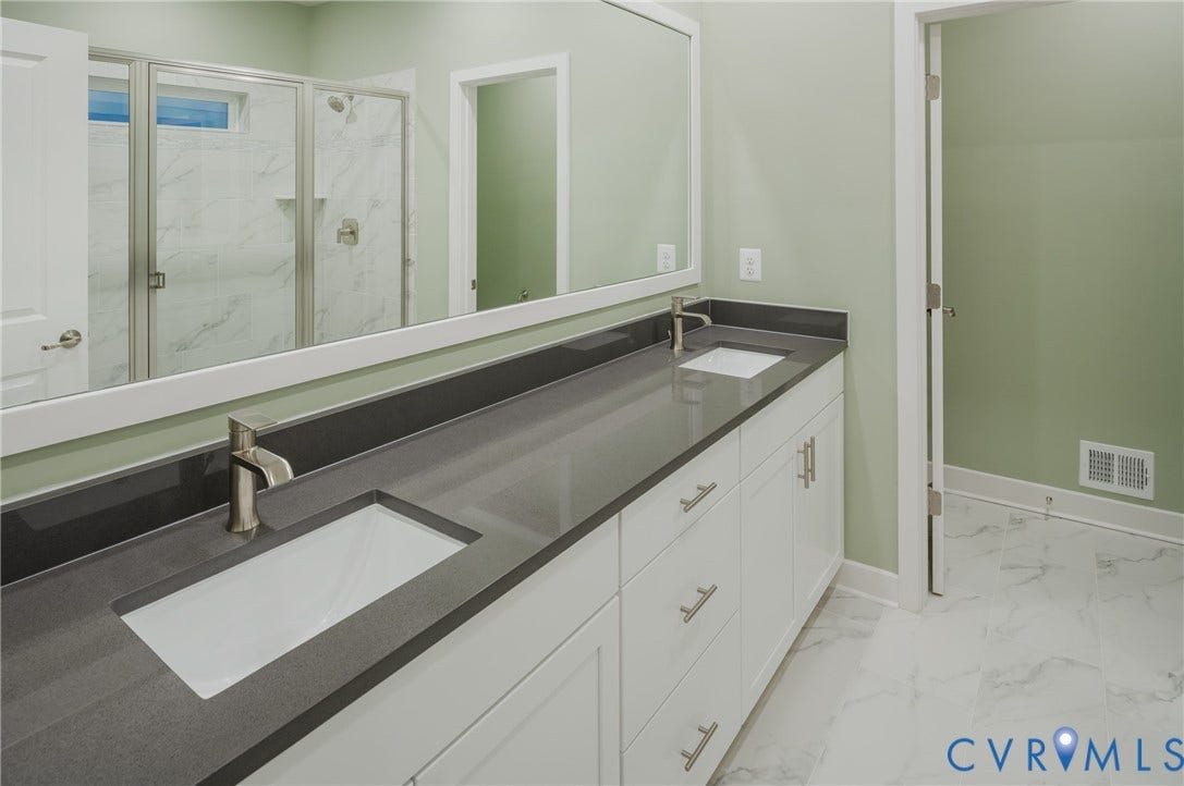White dual vanity with integrated rectangular sinks and brushed nickel faucets, dark stone-finish countertop, and frameless mirror