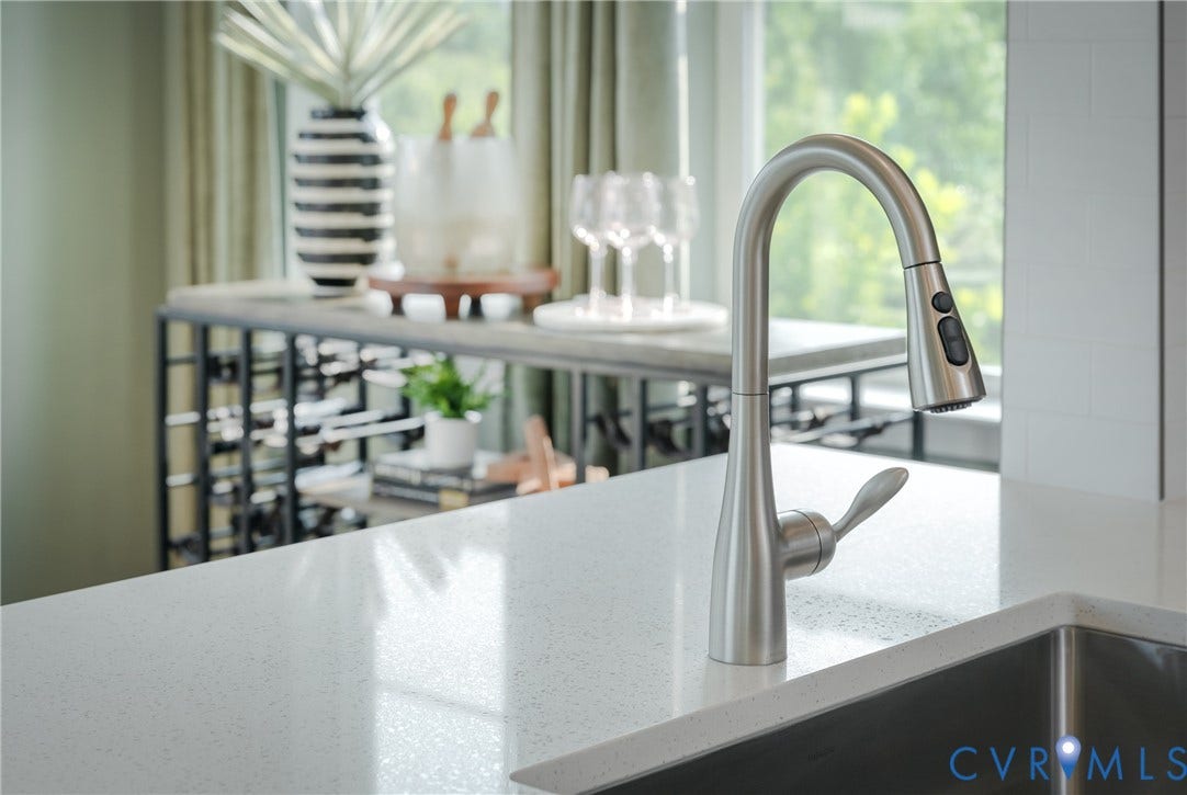 White speckled countertop with an undermount stainless steel sink and a gooseneck pull-down faucet