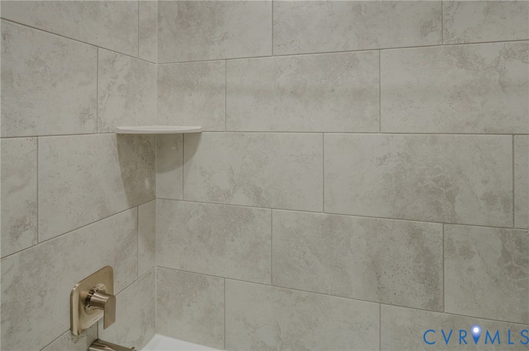 Subway tile shower surround with a corner shelf and brushed nickel fixtures