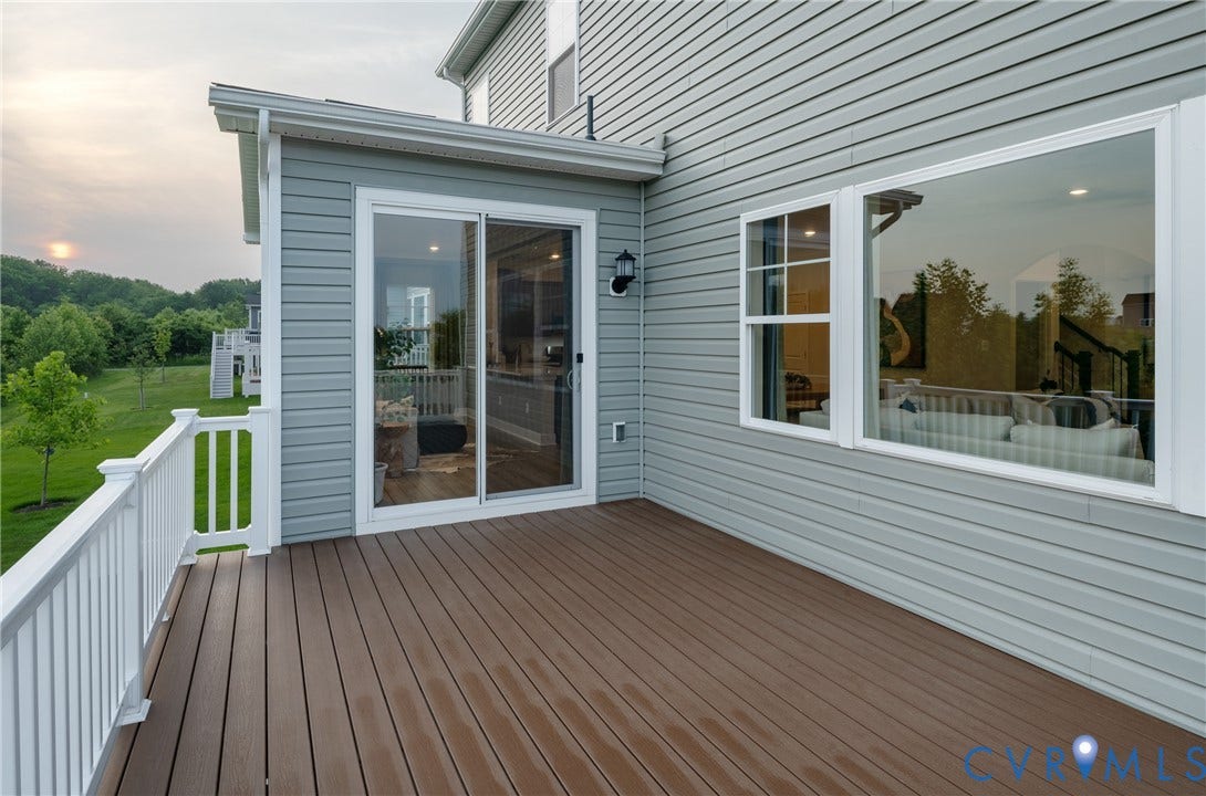 Spacious outdoor deck with composite decking, white railing, sliding glass door, and large windows