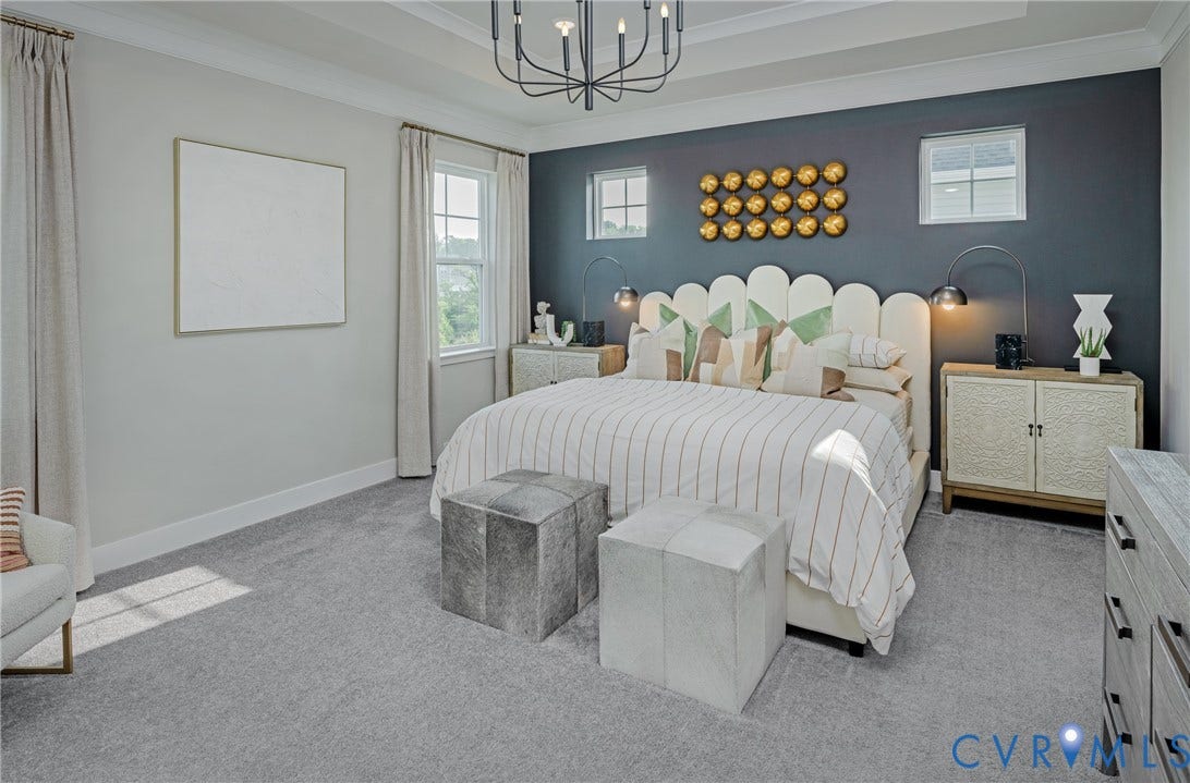 Tray ceiling with a contemporary chandelier, two large windows with drapes, and carpet flooring