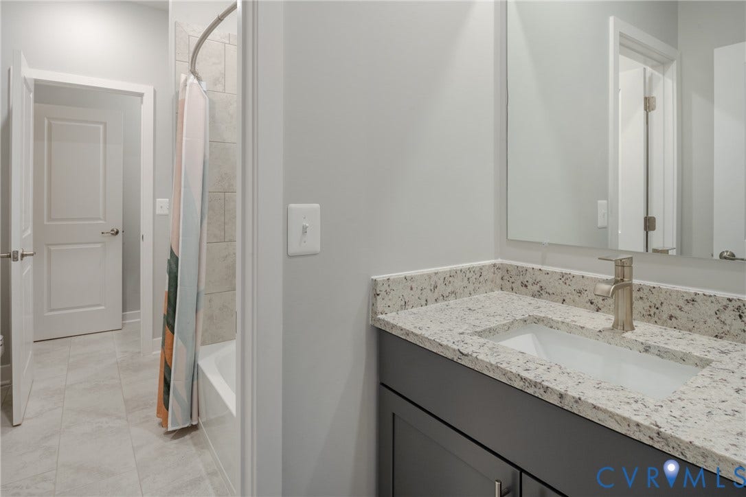 Bathroom featuring a single vanity with stone-finish countertop, under-mount sink, brushed nickel faucet, and a tiled shower/tub combination