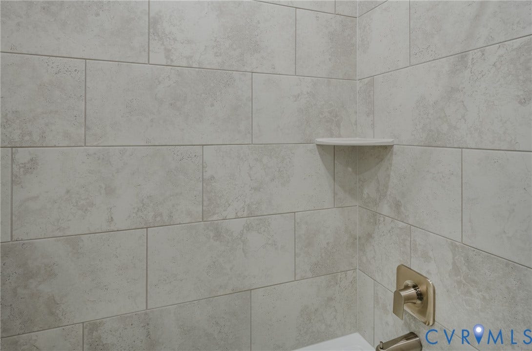 Rectangular tile shower surround with a built-in corner shelf and brushed brass fixtures