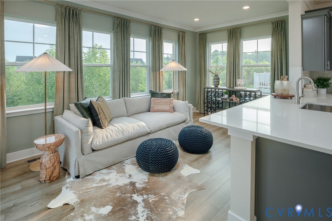 Expansive living area with multiple windows, wood-finish flooring, and recessed lighting