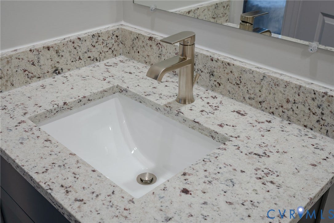 White speckled countertop with an integrated rectangular sink and a brushed nickel faucet