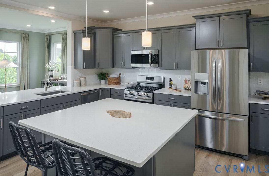 Kitchen featuring shaker-style cabinetry, quartz countertops, stainless steel appliances, and wood-finish flooring