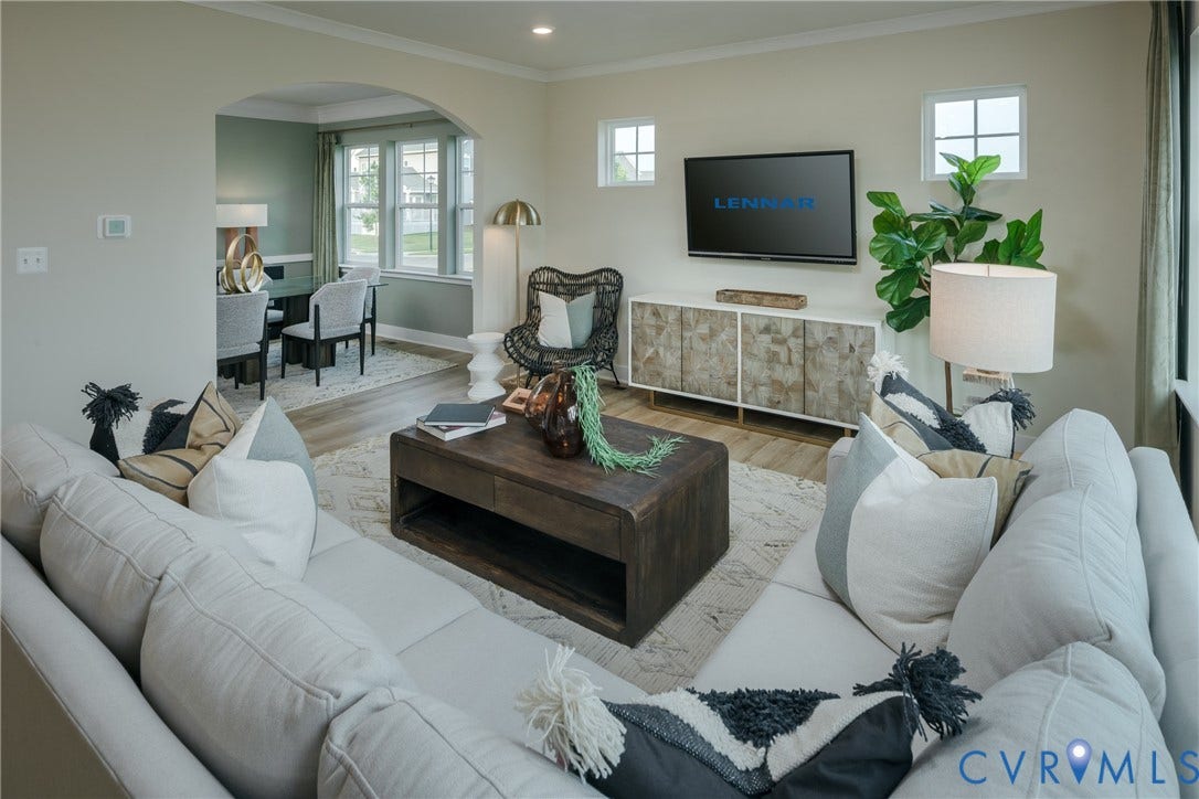 Spacious living area featuring light-toned walls, wood-finish flooring, and an arched doorway