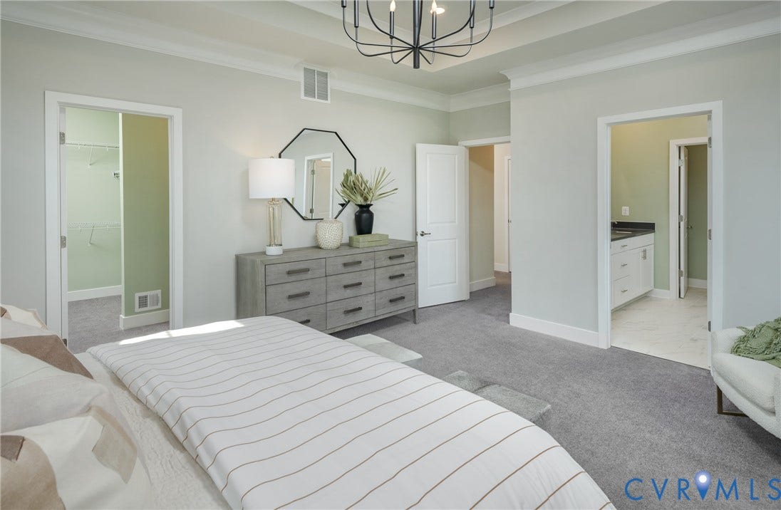 Recessed ceiling with crown molding, tray ceiling, contemporary chandelier, carpeted flooring, and walk-in closet access