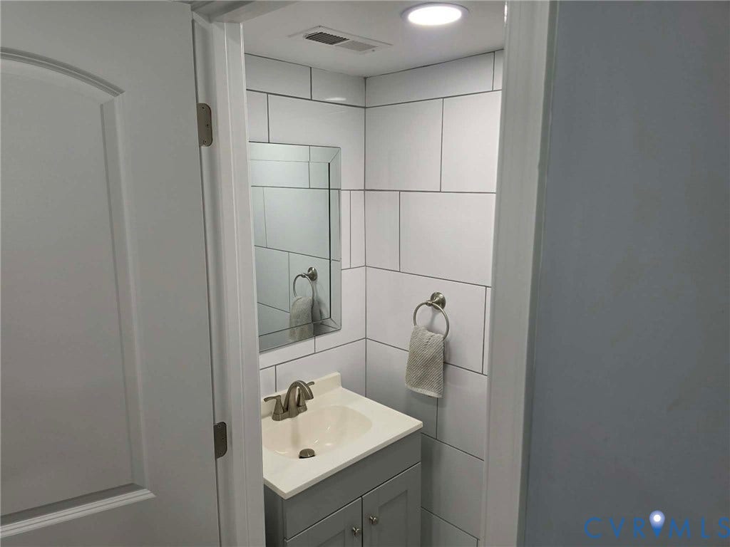 1351 Minefee Street, Bellemeade, Richmond, VA 23224 Downstairs Half bath featuring a gray vanity with sink, toilet and ceramic tile throughout.