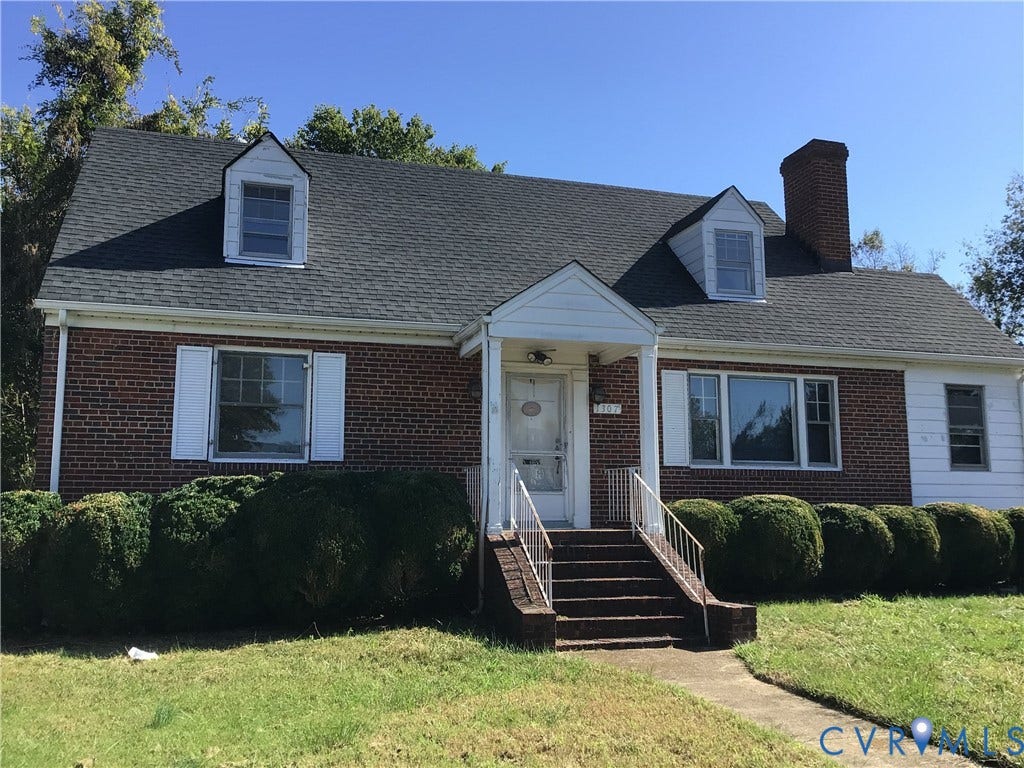 1307 Greystone Avenue, Richmond, VA 23224 Brick and siding exterior featuring a covered front entryway, asphalt shingle roof, two dormer windows, and a brick chimney