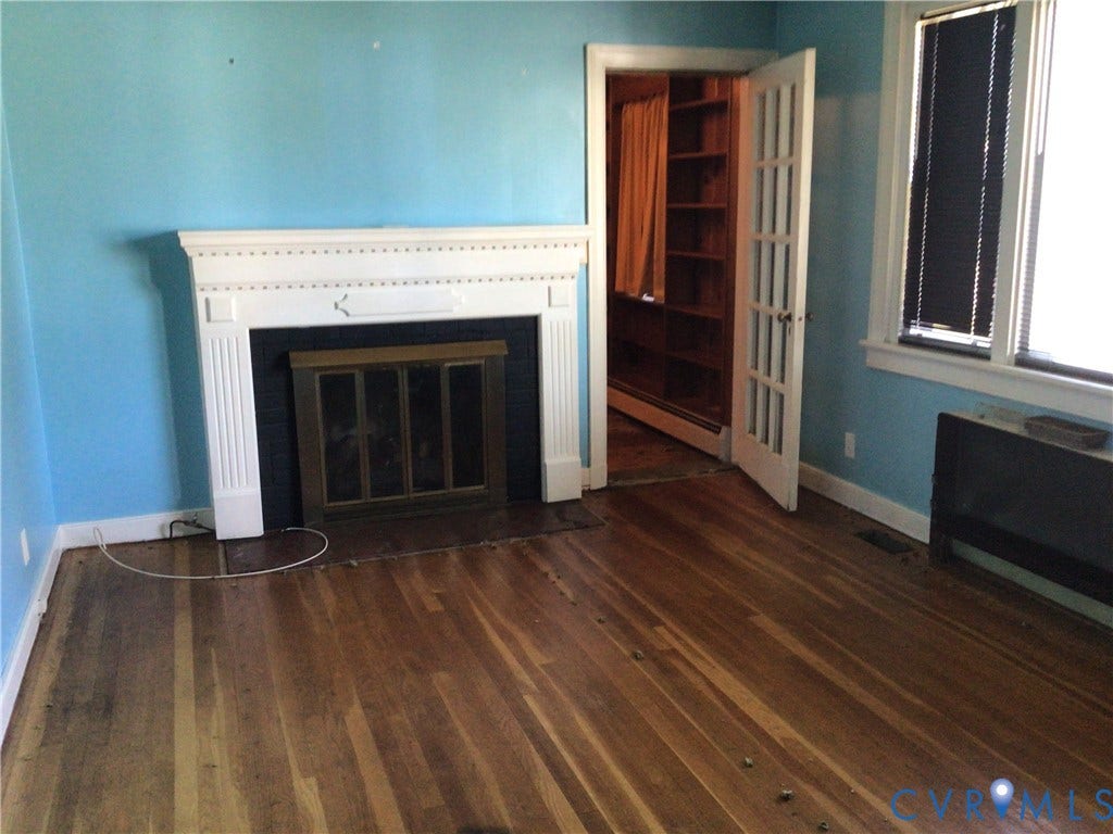 1307 Greystone Avenue, Richmond, VA 23224 Fireplace featuring a white decorative mantel, wood-finish flooring, French-style interior door, and built-in wooden shelving