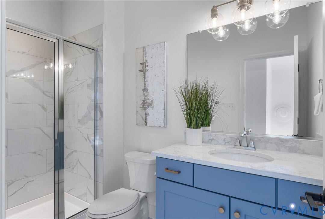 2831 Old Pump Road, The Preserve At John Rolfe, Henrico, VA 23233 Bathroom featuring a glass-enclosed shower with tiled walls, a vanity with a light-toned countertop, a rectangular mirror, and a wall-mounted light fixture